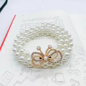 Detail of multi-layer pearl waist belt featuring a gold rhinestone-encrusted bow design