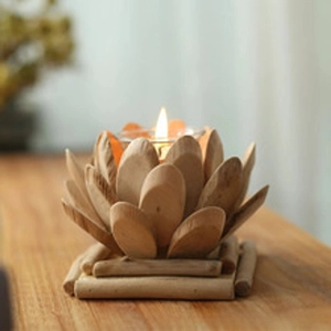 Macro detail of lotus shaped wooden candle holder with glass cup and lit white tealight