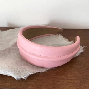 Close-up of pink leather headband with horizontal stitching on a rustic linen cloth