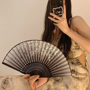 Close-up of folding bamboo fan with black-grey gradient and floral pattern details