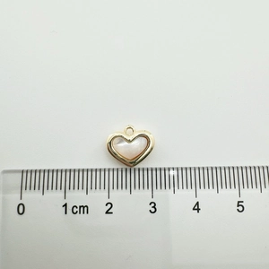 18K gold-plated heart pendant with white shell inlay shown on a ruler for scale