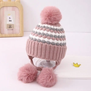 Detalle del tejido de punto del gorro de invierno rosa a rayas con suaves pompones
