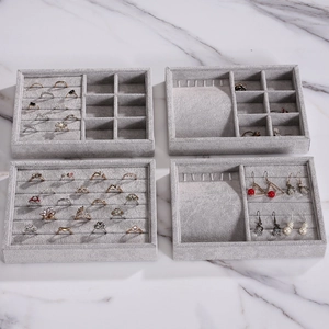 Gray velvet jewelry organizer trays set on marble background for rings and earrings