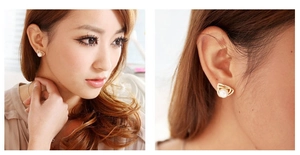 Detail of gold geometric triangle stud earrings with white pearl on a female model