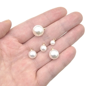 White ABS faux pearl charms with gold rings in hand showing various size comparisons