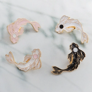 Detailed view of four koi fish enamel pins in pink, white, and black with gold plating