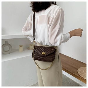Close-up of dark brown quilted crossbody bag with gold chain strap and lock detail