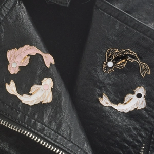 Pink, white, and black koi fish enamel pins set on black leather jacket lapel