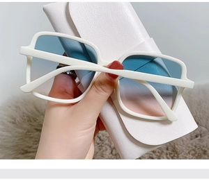 Close-up of white square sunglasses with blue-pink gradient lenses on leather case