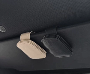 Close-up of beige and black PU leather sunglasses holders clipped on car sun visor