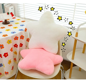 Detail showing soft white and pink star plush pillows in a cozy home setting