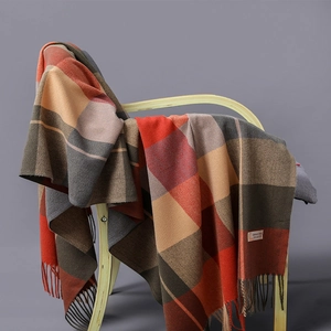 Plaid cashmere blend scarf with long tassels draped on a modern wooden chair