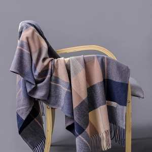 Detail of plaid cashmere blend scarf with tassels draped on a wooden chair