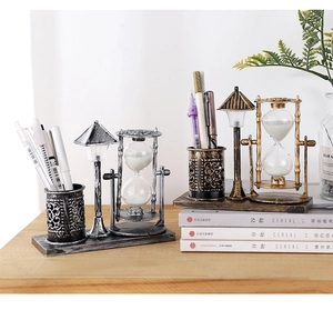 Detail shot of vintage metal pen holder with hourglass and night light on wooden desk