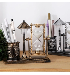 Close-up of vintage bronze pen holder with glass hourglass and miniature street lamp detail