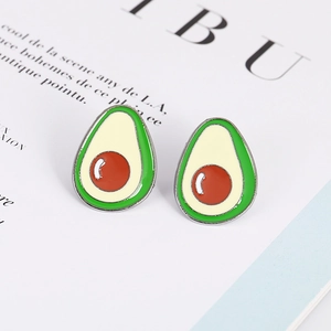 Cute cartoon avocado enamel pin with dark green shell and yellow flesh on minimalist magazine