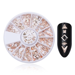 Rose gold metal nail art studs in stars and geometric shapes displayed on black nails