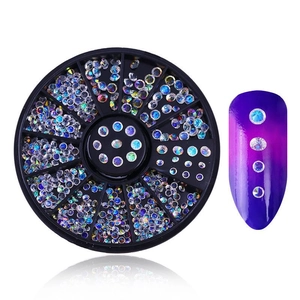 Detailed view of iridescent nail art rhinestones in a storage wheel with a sample nail