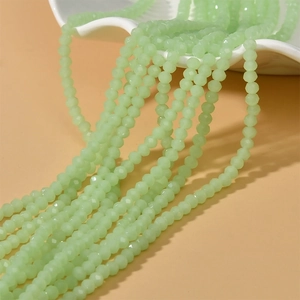 Pale green faceted rondelle beads 4mm for DIY jewelry making displayed on a ceramic plate