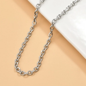 Close-up of silver-toned metal O-chain and links draped over a white ceramic piece