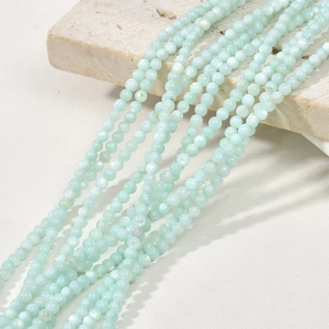 Macro view of 3mm light blue natural freshwater shell beads on a textured stone