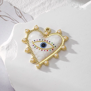 Golden heart pendant with evil eye pattern and pearl border on white textured stone