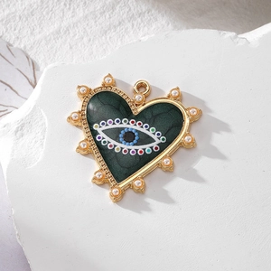 Macro detail of heart-shaped evil eye pendant with pearls and green marble finish