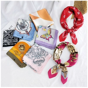 Detail of assorted silk-feel square scarves featuring retro chain and paisley patterns