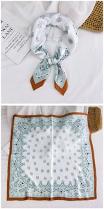 Detailed view of square silk scarf with teal paisley pattern and elegant brown border
