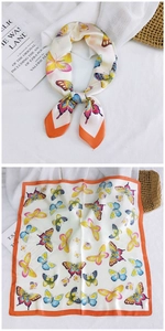 Detail of a square silk scarf with butterfly print and orange borders on white background