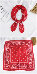 Detail showing red paisley square scarf tied and laid flat on white linen background