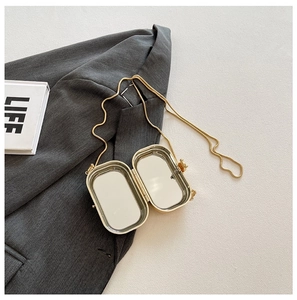 Close-up of golden acrylic lipstick bag featuring a built-in mirror and chain strap