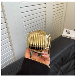 Close-up of gold mini acrylic clutch bag with vertical stripe texture and chain