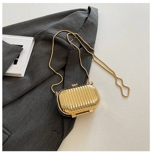 Close-up of gold hard shell evening bag with vertical stripes and metallic chain strap
