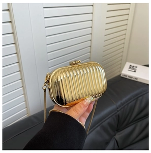 Detailed shot of gold acrylic lipstick bag with pleated texture and snake chain strap