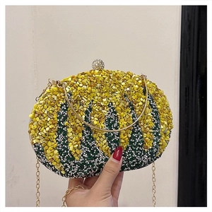 Detail of evening clutch bag featuring yellow stones, green crystals and gold chain strap