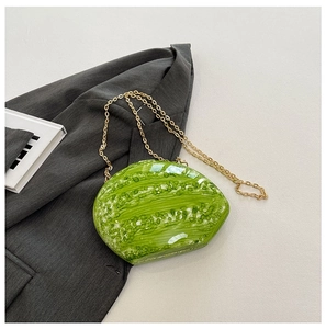 Detail of green acrylic shell evening bag with gold chain on grey blazer