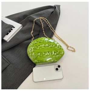Detail shot of a green leaf-shaped acrylic evening bag with a gold metal chain strap