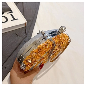 Detail of luxury evening clutch with orange crystals, silver frame and rhinestone closure