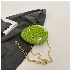 Detailed macro view of vibrant watermelon-shaped evening bag with a gold metal chain strap