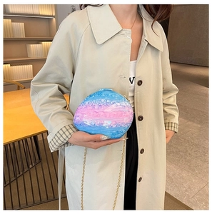 Fashionable blue and pink gradient acrylic shell clutch with gold chain on beige coat