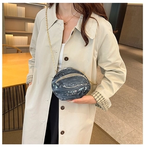 Detail of grey marble acrylic evening bag with gold chain strap on a model shoulder
