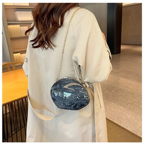 Detail of dark grey marble acrylic evening bag with shiny finish and gold chain strap