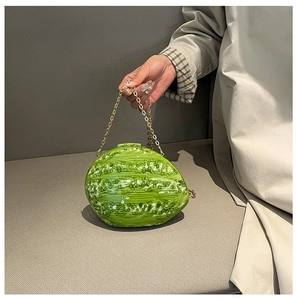 Macro shot of watermelon shaped evening clutch with green textured shell and gold chain strap