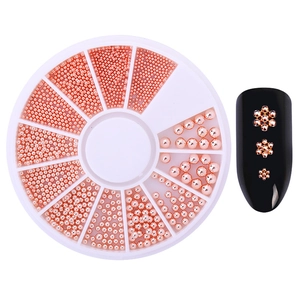 Detail of rose gold metal nail art beads in a white storage disc with various sizes