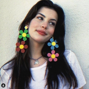 Acrylic colorful sunflower earrings with layered petals worn by a model against white wall