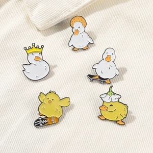 Set of 5 cartoon yellow duck enamel pins with crown and skateboard on white fabric