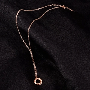 Close-up of a 18K rose gold triple ring pendant necklace on black silk fabric