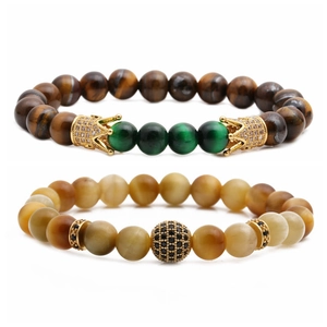Dettaglio del set di braccialetti con pietre occhio di tigre e ciondolo a corona dorata