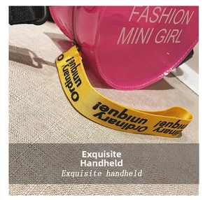 Detailed macro of pink transparent mini bag with yellow strap saying Ordinary Unique